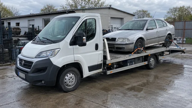 Bílý odtahový vůz s upevněným vozidlem Škoda na hliníkové plošině